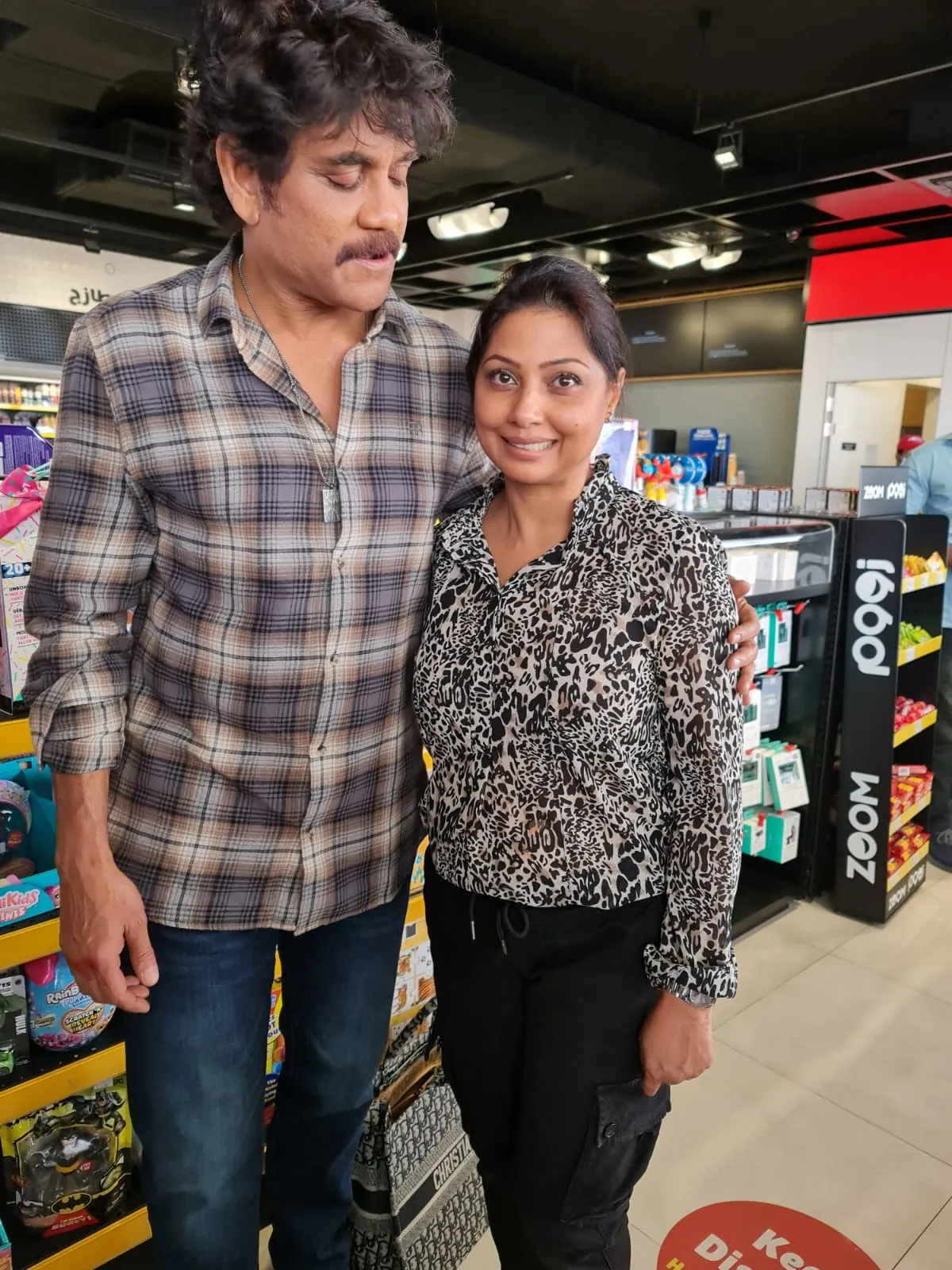 Man in a plaid shirt leaning in beside a woman in an animal-print top in a shop aisle