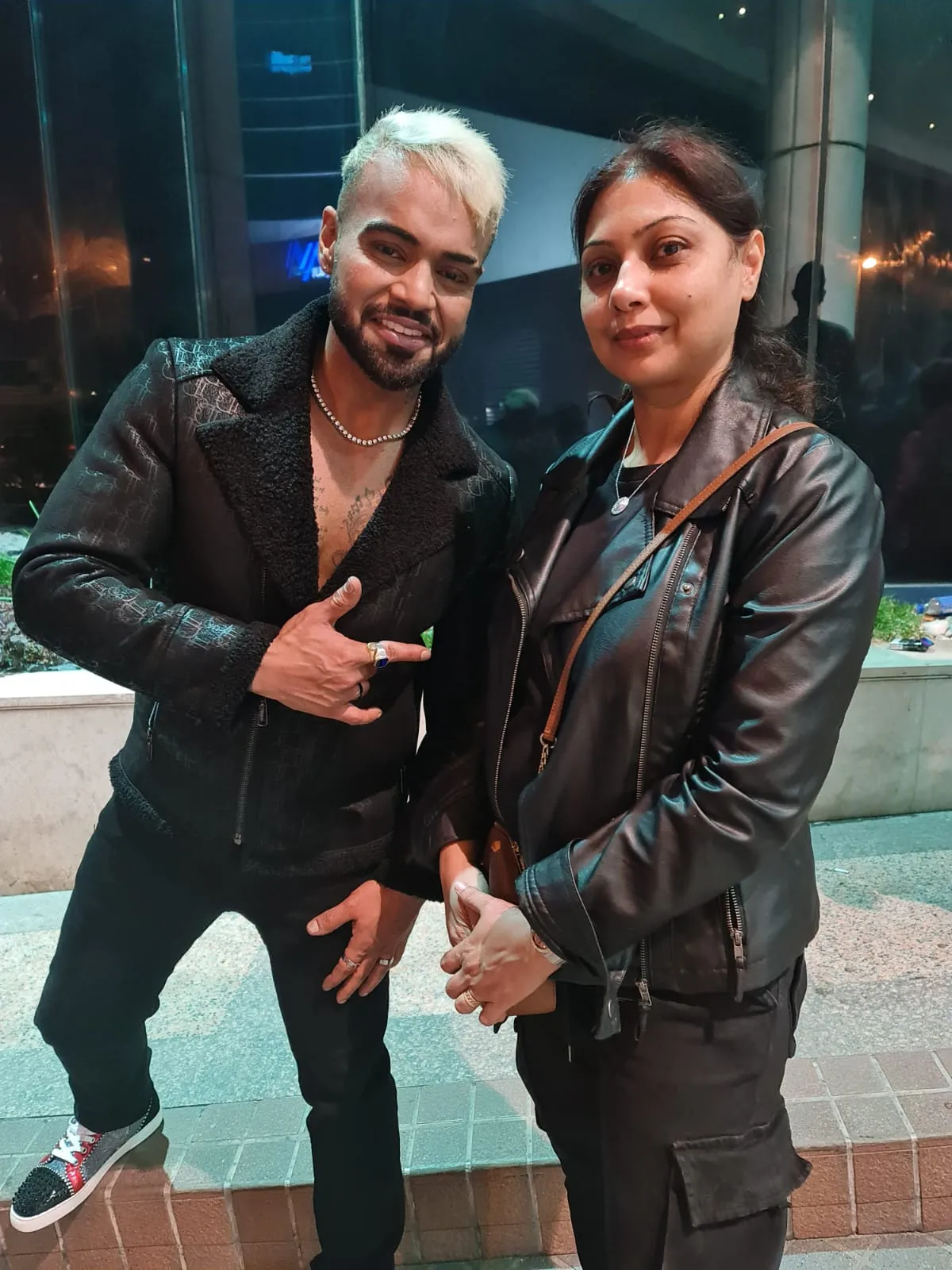 Man with silver-white hair in a black leather jacket posing with a woman in a black leather jacket