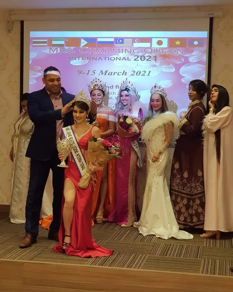 Group photo on a stage at an event, people in formal wear and sashes