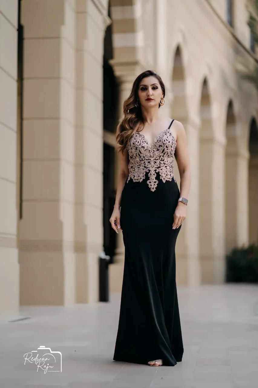 Woman in a long black dress with an embellished bodice standing in an arched stone colonnade