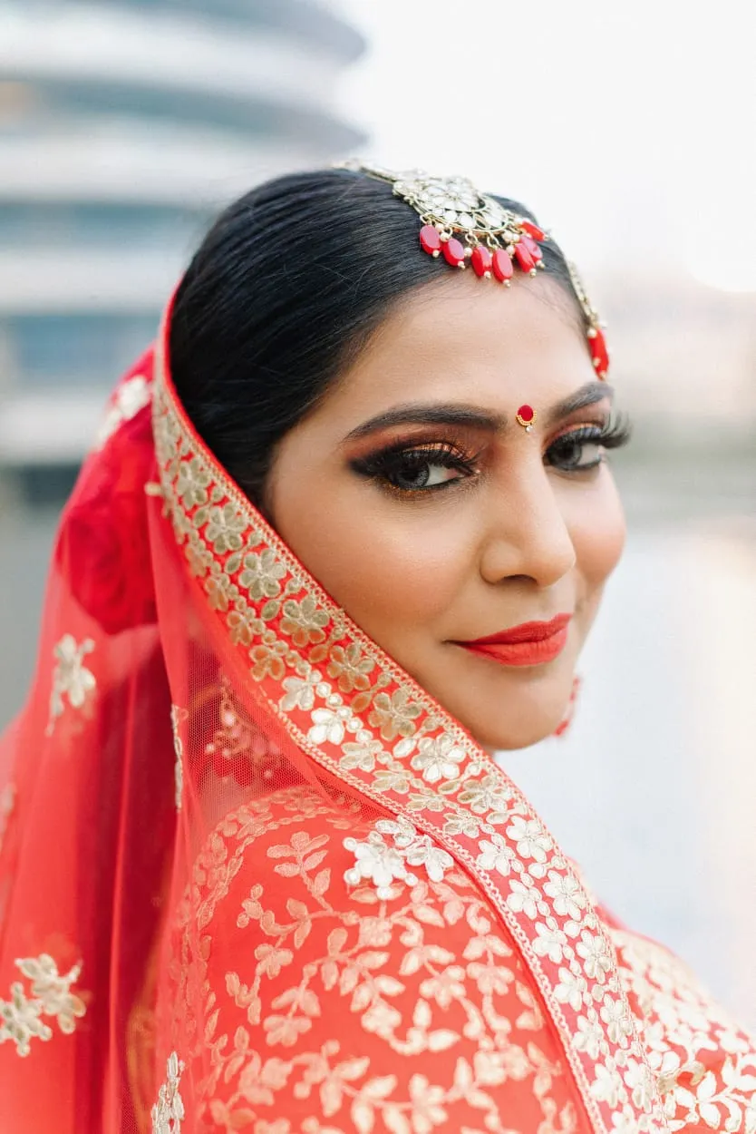 Close-up of a bride in a red dupatta with red bridal makeup and gold jewellery