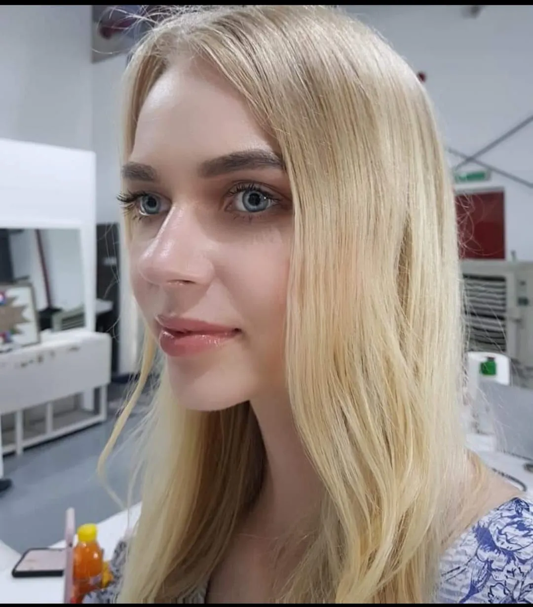 Woman with long blonde hair and natural makeup in a bright white room