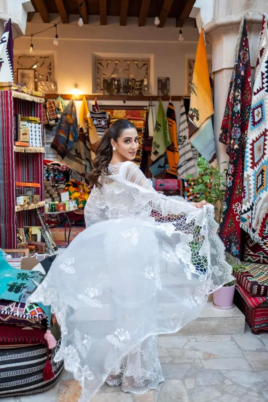 Woman in a white tulle dress seated in a colourful market-style shop