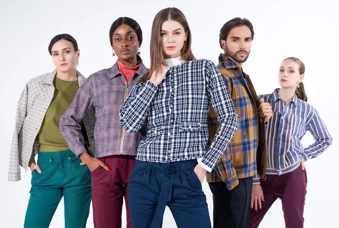 Six models in checked shirts and trousers standing together on a white background