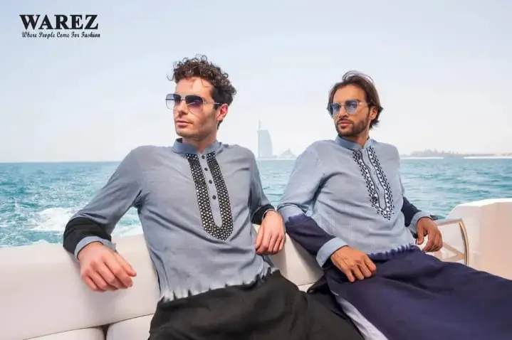 Two men in sunglasses and grey-blue outfits sitting on a boat deck