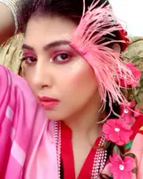 Woman with a pink feather and pink flower headpiece, bold makeup and a pink dupatta