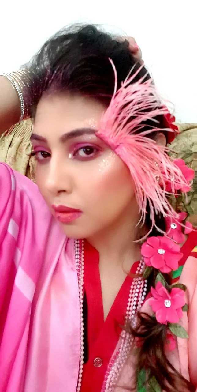 Woman with a pink feather and pink flower headpiece, bold makeup and a pink dupatta