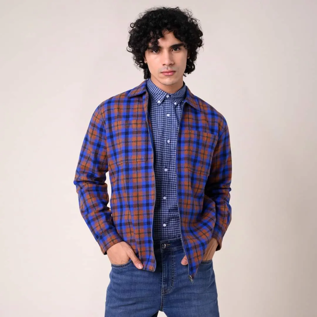 Young man with curly hair in a blue and orange checked shirt over a blue top