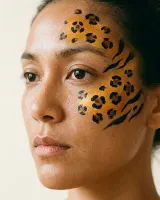 AI-generated reference for the Bold animal prints idea: orange and black leopard spots and tiger stripes painted on the cheek and forehead