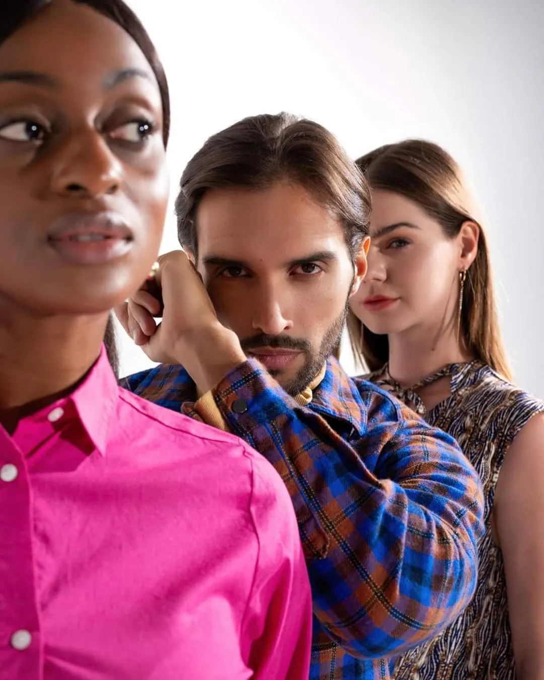 Three models in bold colours posed together at a fashion shoot